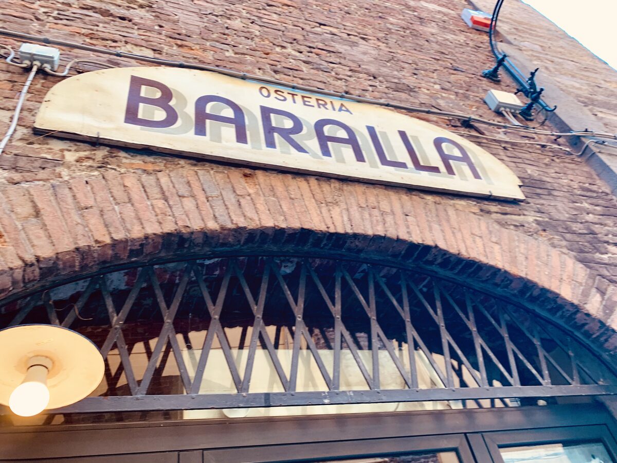 Osteria Baralla exterior sign on historic brick wall in Lucca
