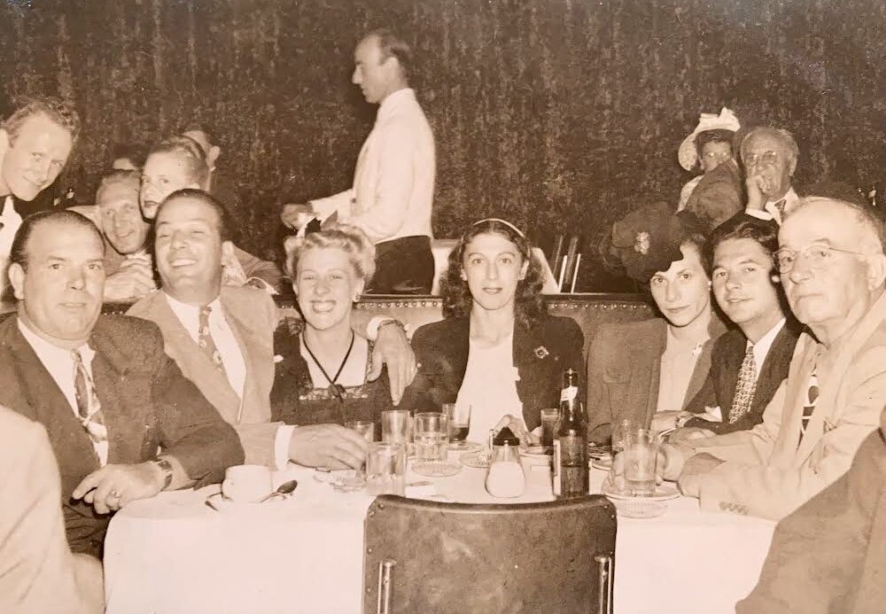 Family gathered at a restaurant table with grandfather and great-grandfather