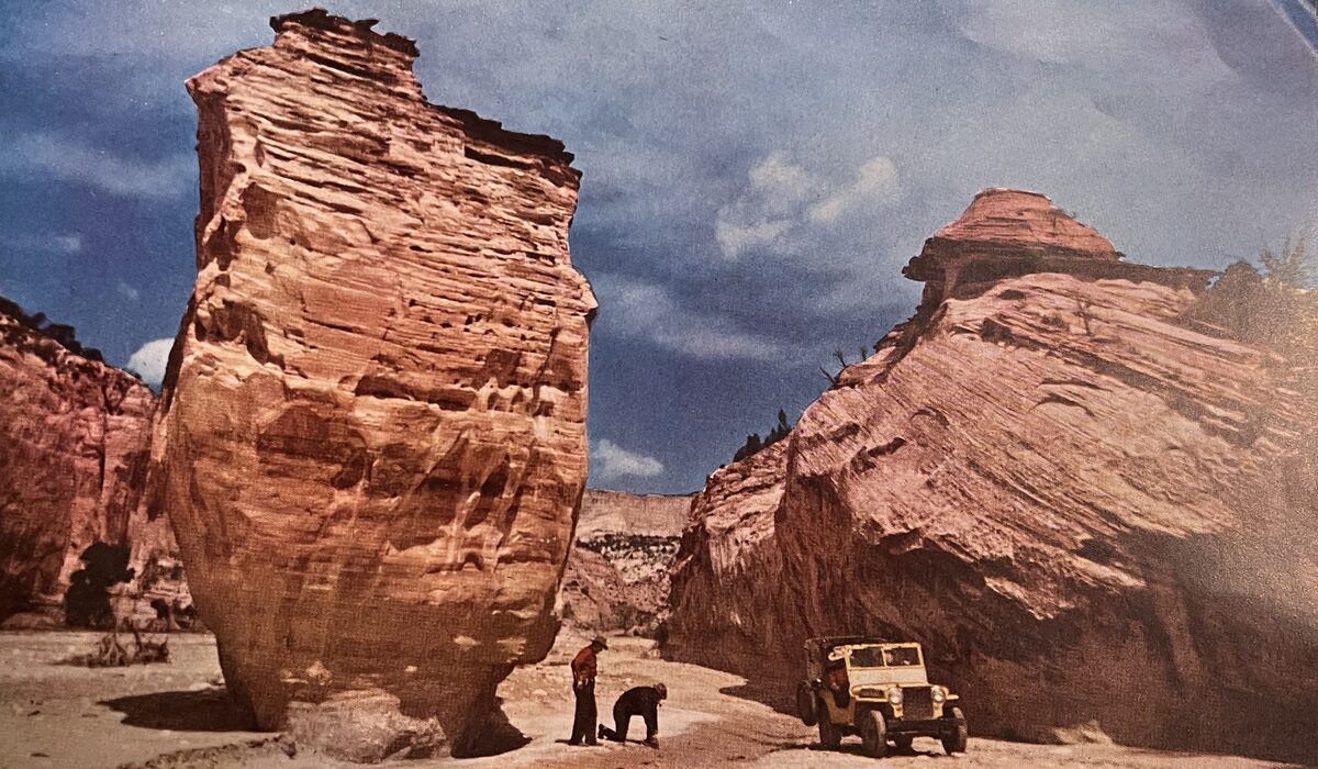Explorers and vintage yellow jeep between sandstone formations