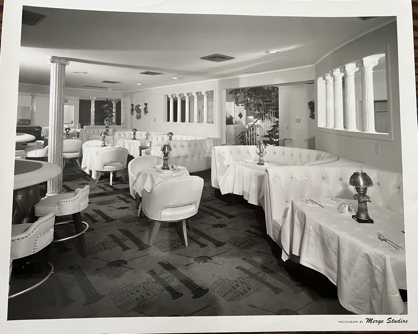 Roman-themed interior of Quo Vadis Hollywood with white booths and classical columns